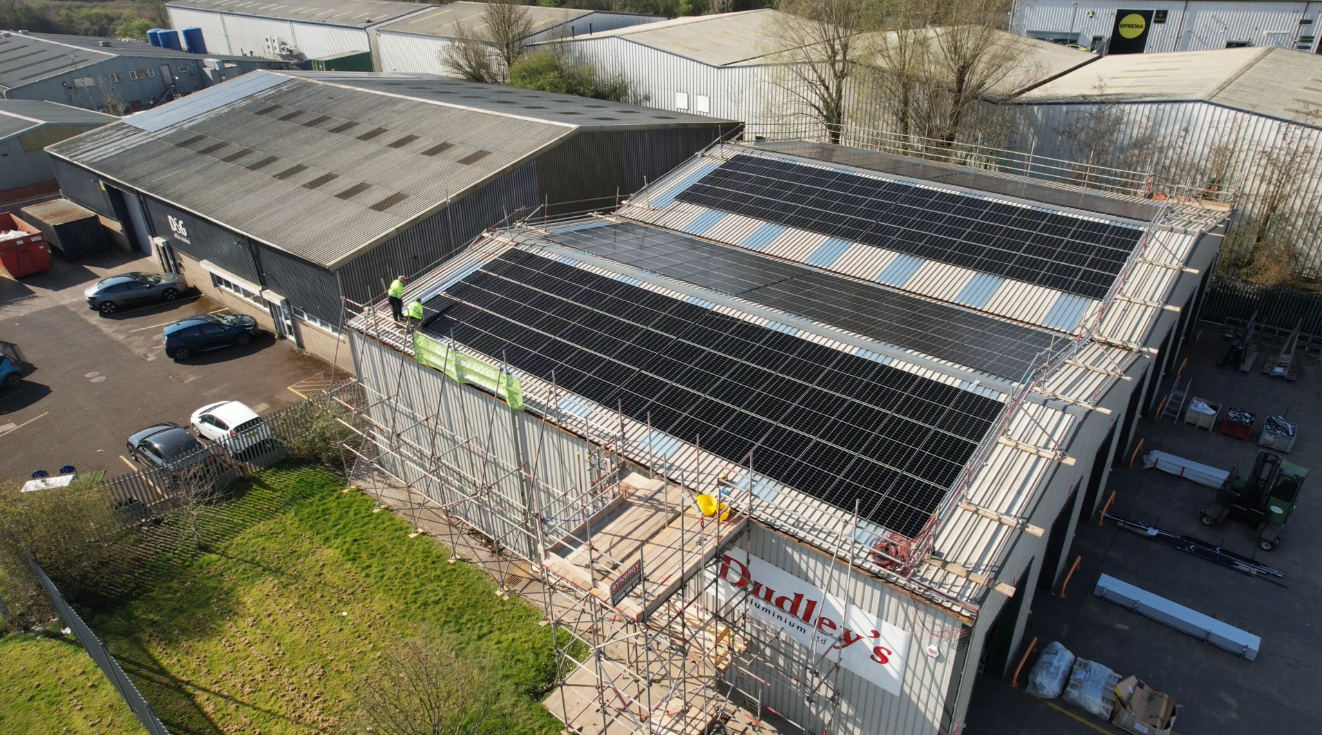 Installers fitting solar panels on the roof of Dudley's Aluminium in Cardiff, with scaffolding and edge protection in place during the install