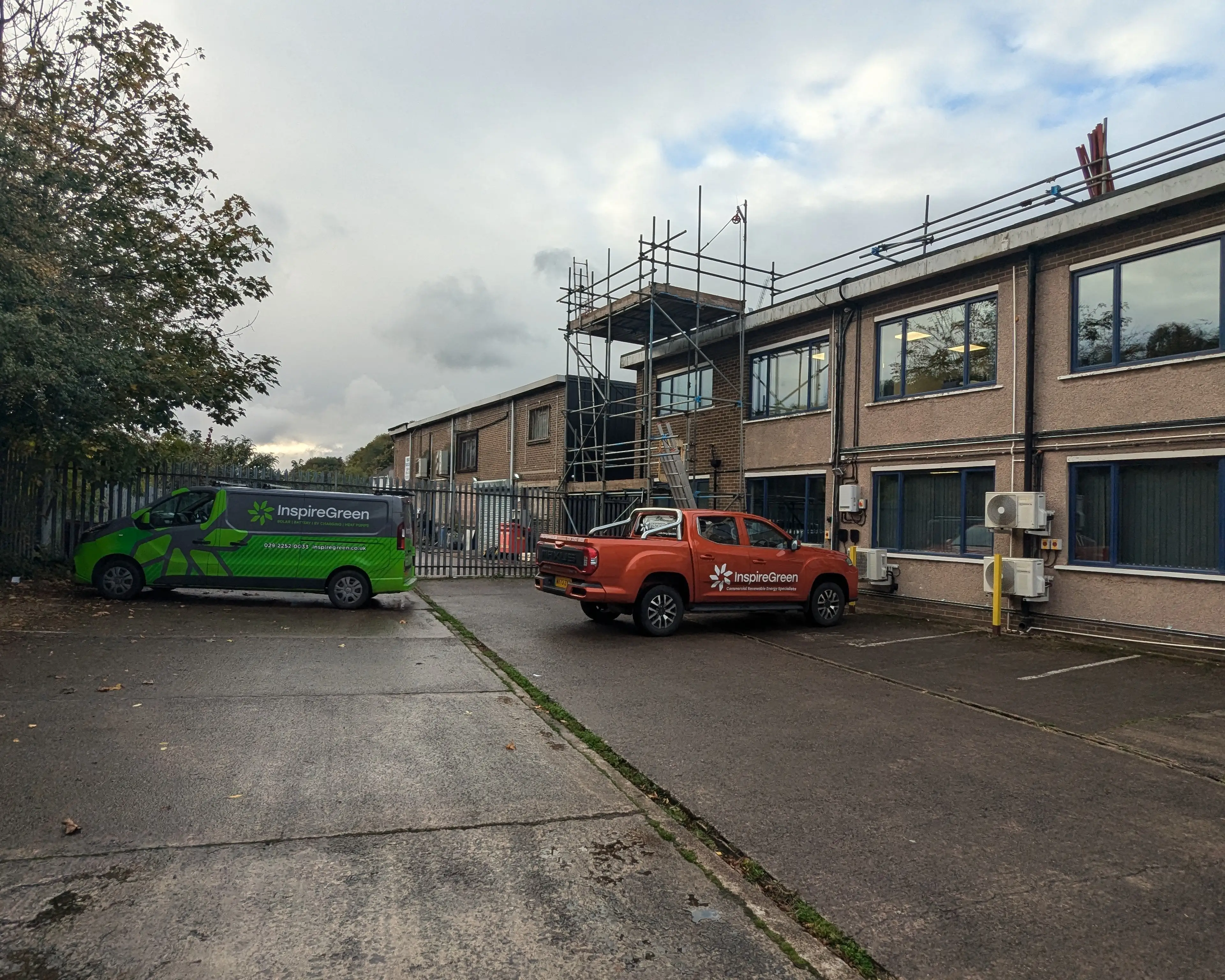 InspireGreen vehicles outside iTec Skills' Cardiff head office, with scaffolding in place during the solar PV install