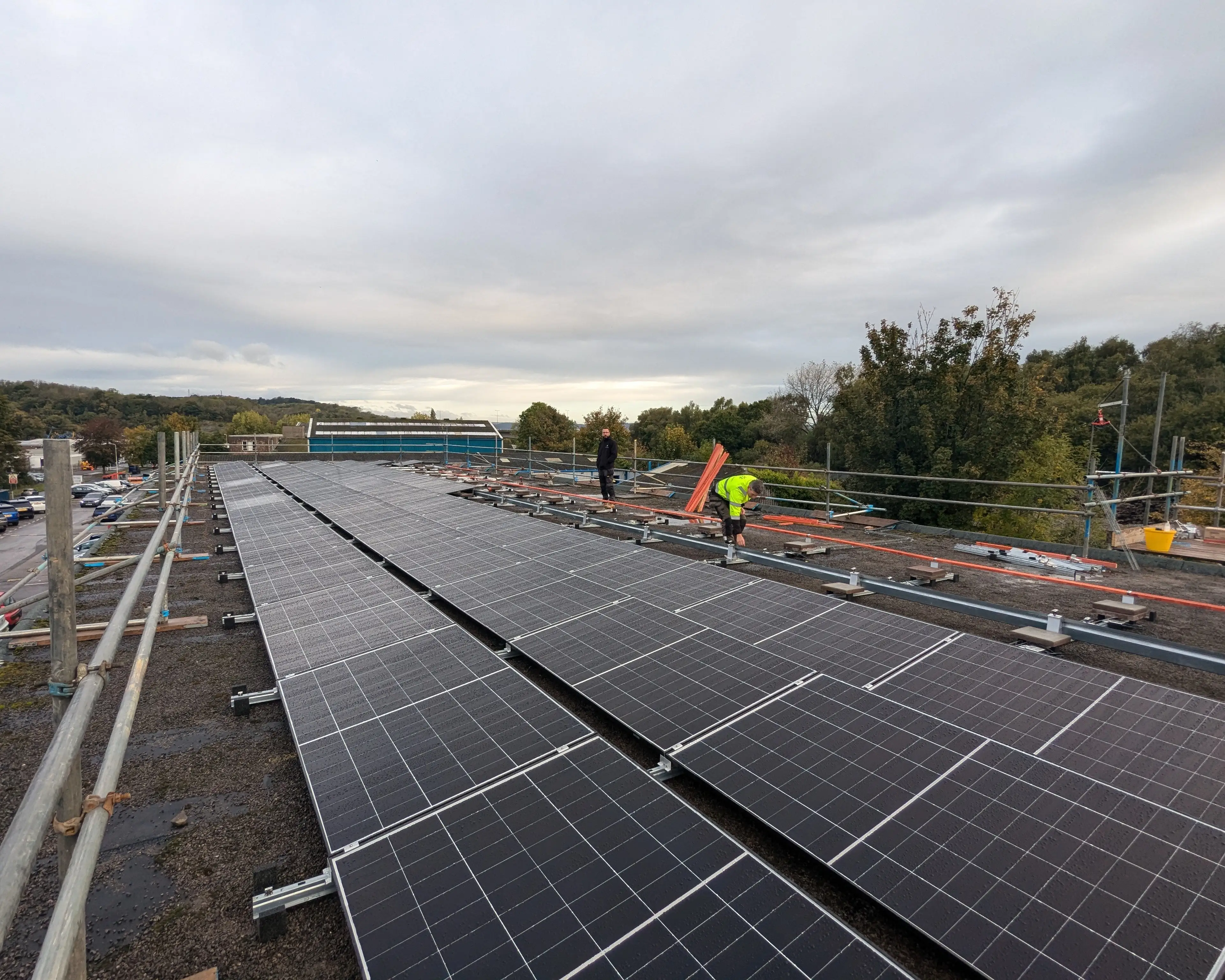 Installers fitting the rooftop solar PV array at iTec Skills' head office in Cardiff, with scaffolding and edge protection in place during the installation