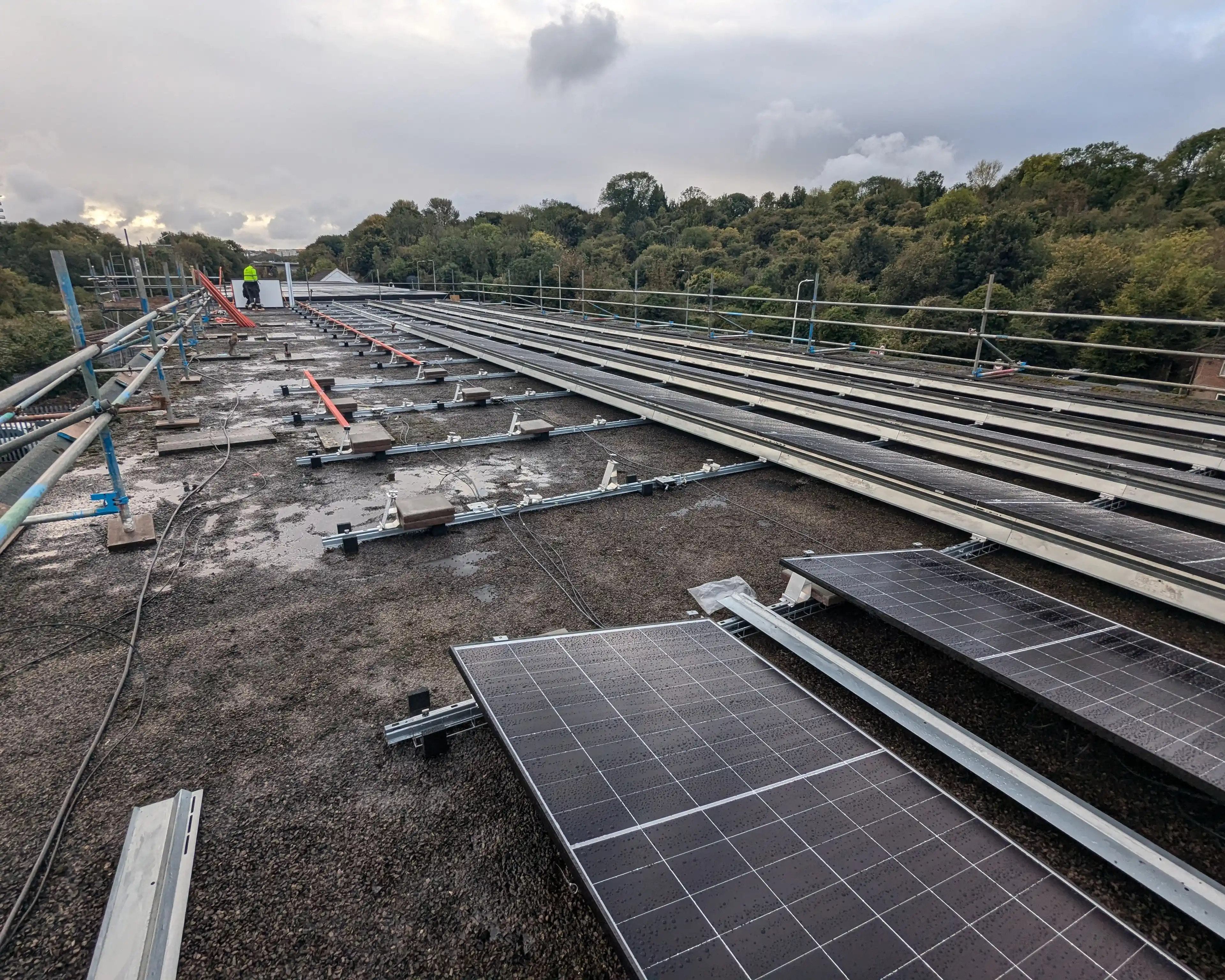 Mounting rails and the first solar panels being laid out on the flat roof of iTec Skills' head office in Cardiff during the installation