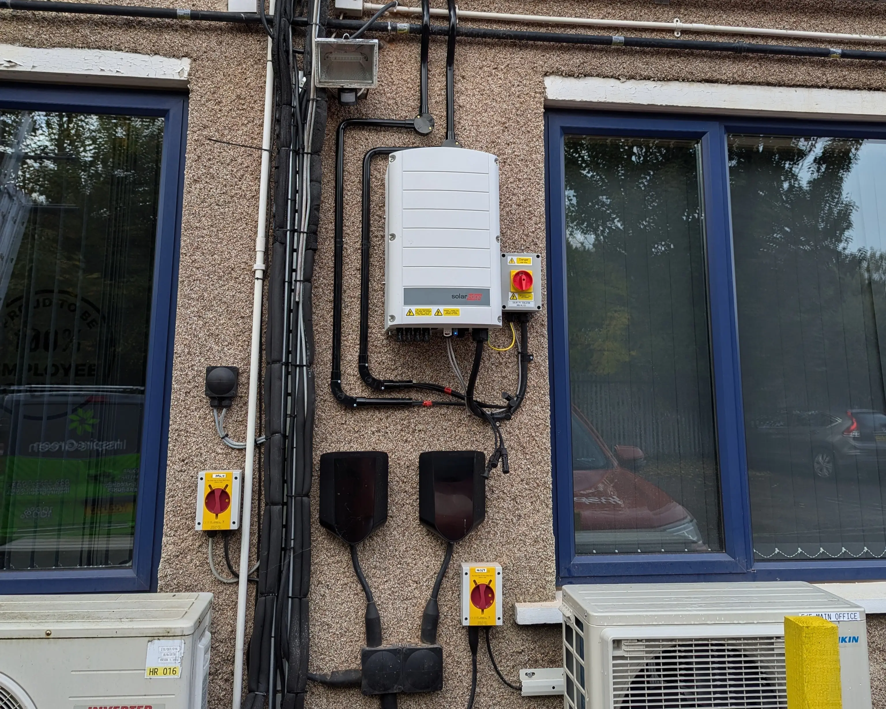 SolarEdge inverter and DC isolators mounted on the exterior wall of iTec Skills' head office in Cardiff, part of the completed solar PV system