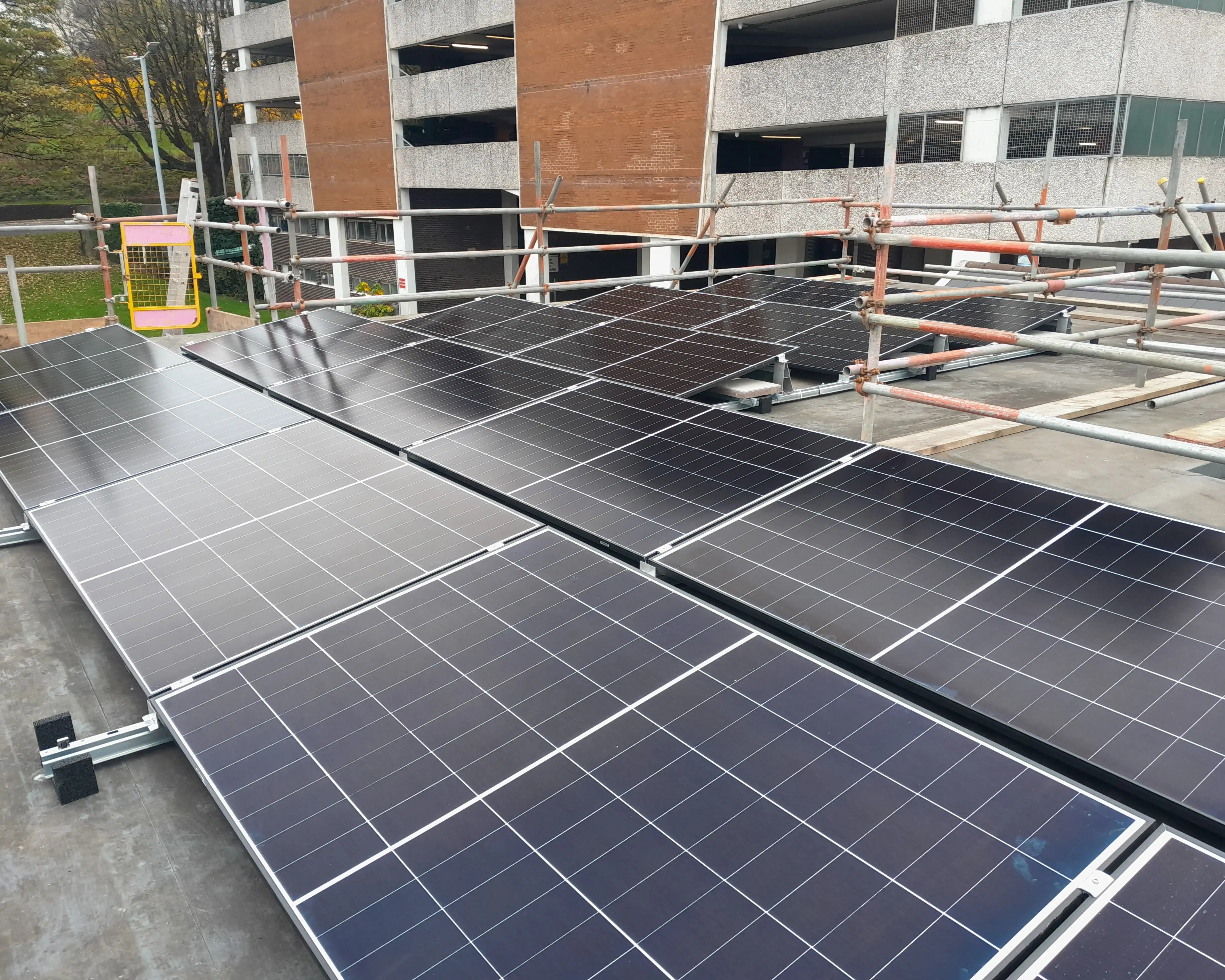 Solar PV panels installed on the flat roof of iTec Skills' training centre in Newport, with scaffolding and edge protection in place