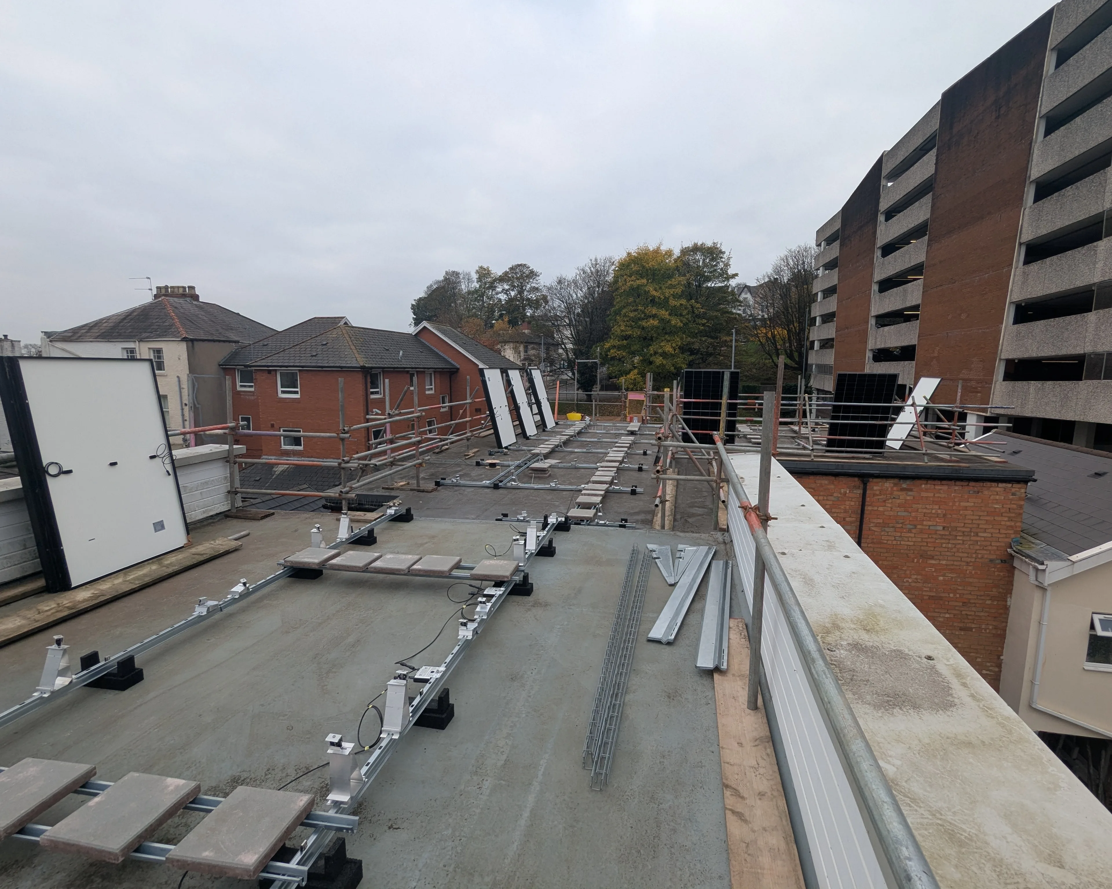 The ballasted mounting framework being laid out on the flat roof of iTec Skills' training centre in Newport at an early stage of the solar PV installation, with panels and rails ready to fit