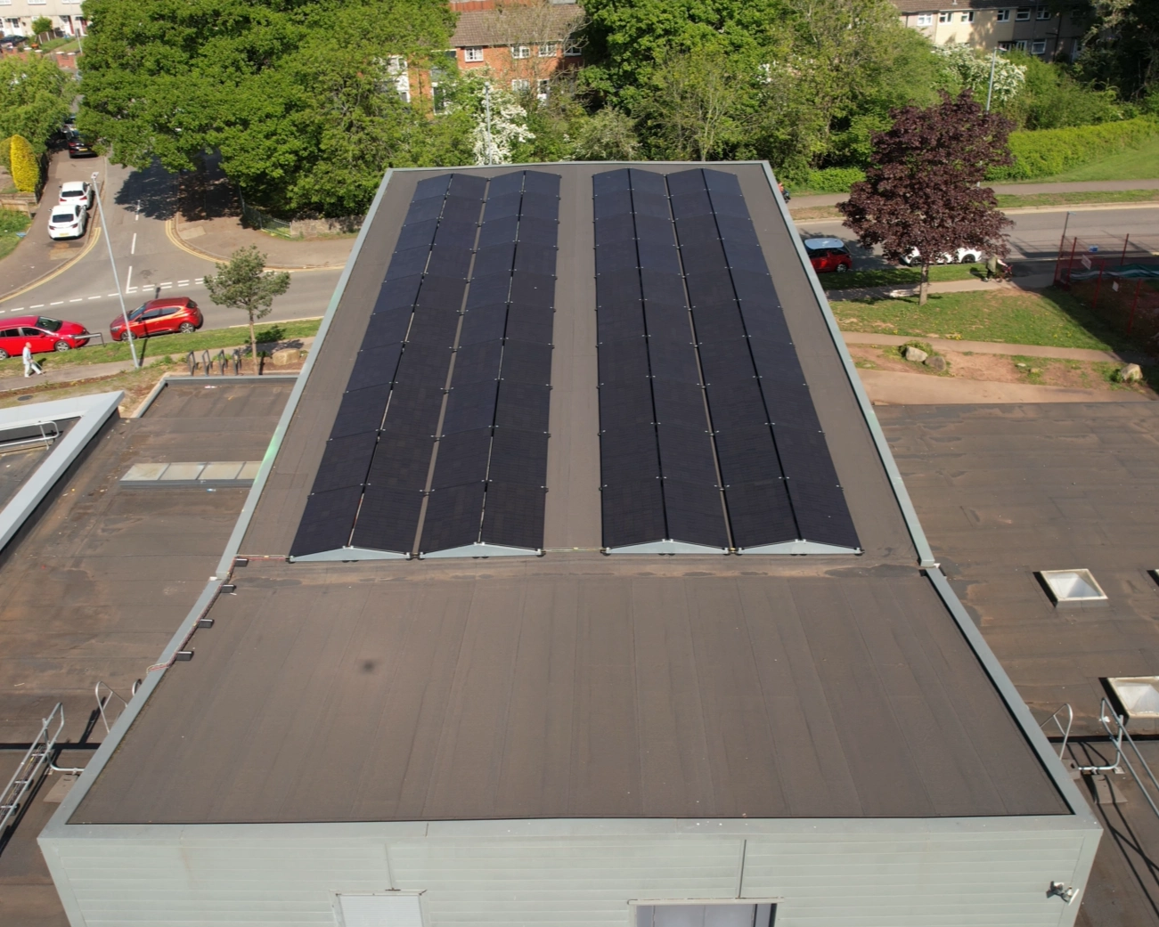 Rows of solar panels on the main roof of Ringland Community Centre in Newport, with the surrounding estate behind.