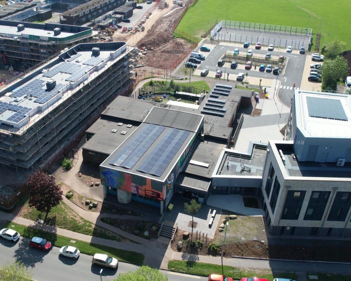 Aerial view of solar panels on the roofs of Ringland Community Centre in Newport, with the mural-fronted building and surrounding estate in view.