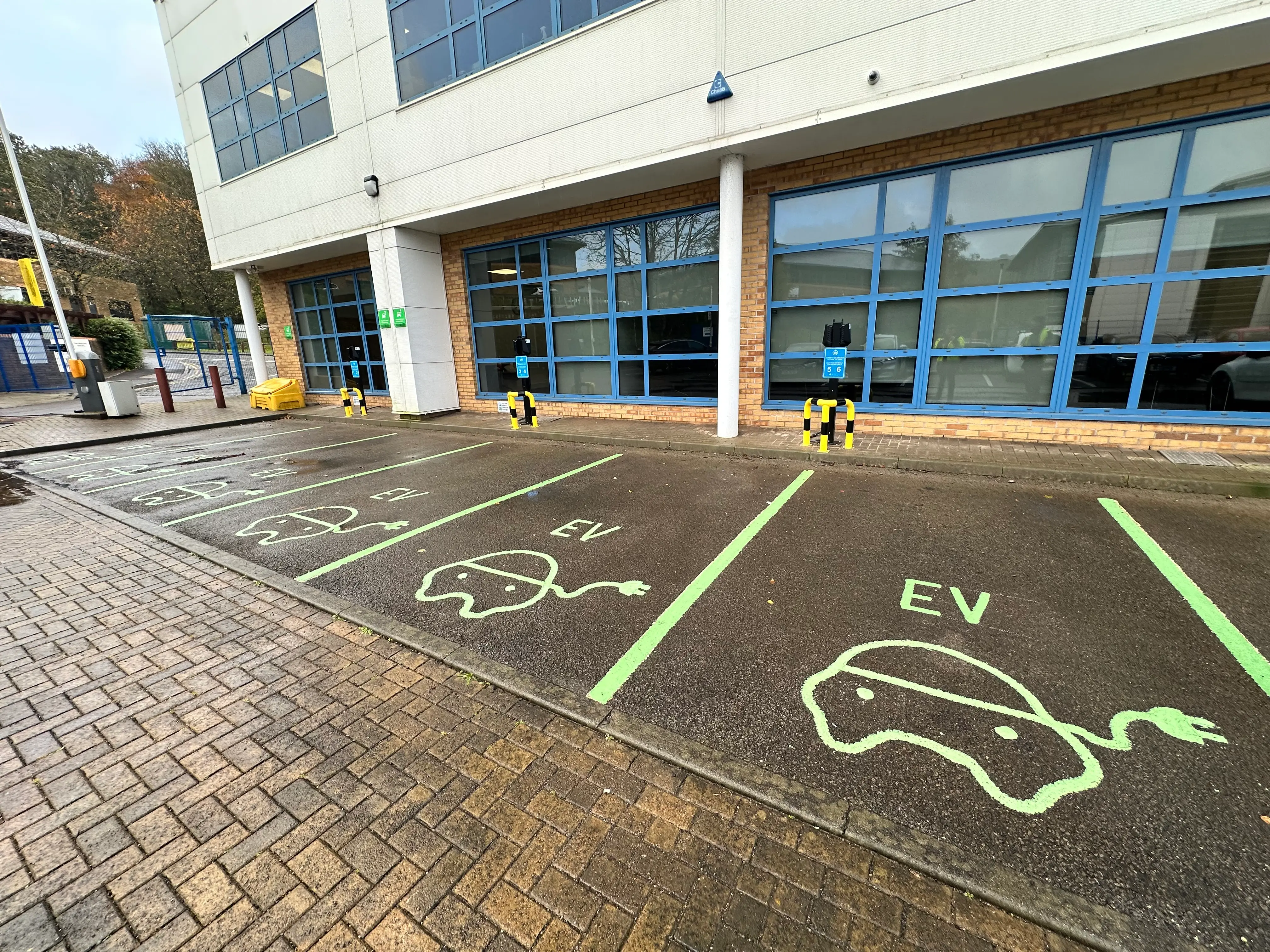 Commercial EV charging installation with multiple bays, painted markings and protective bollards at a workplace car park.