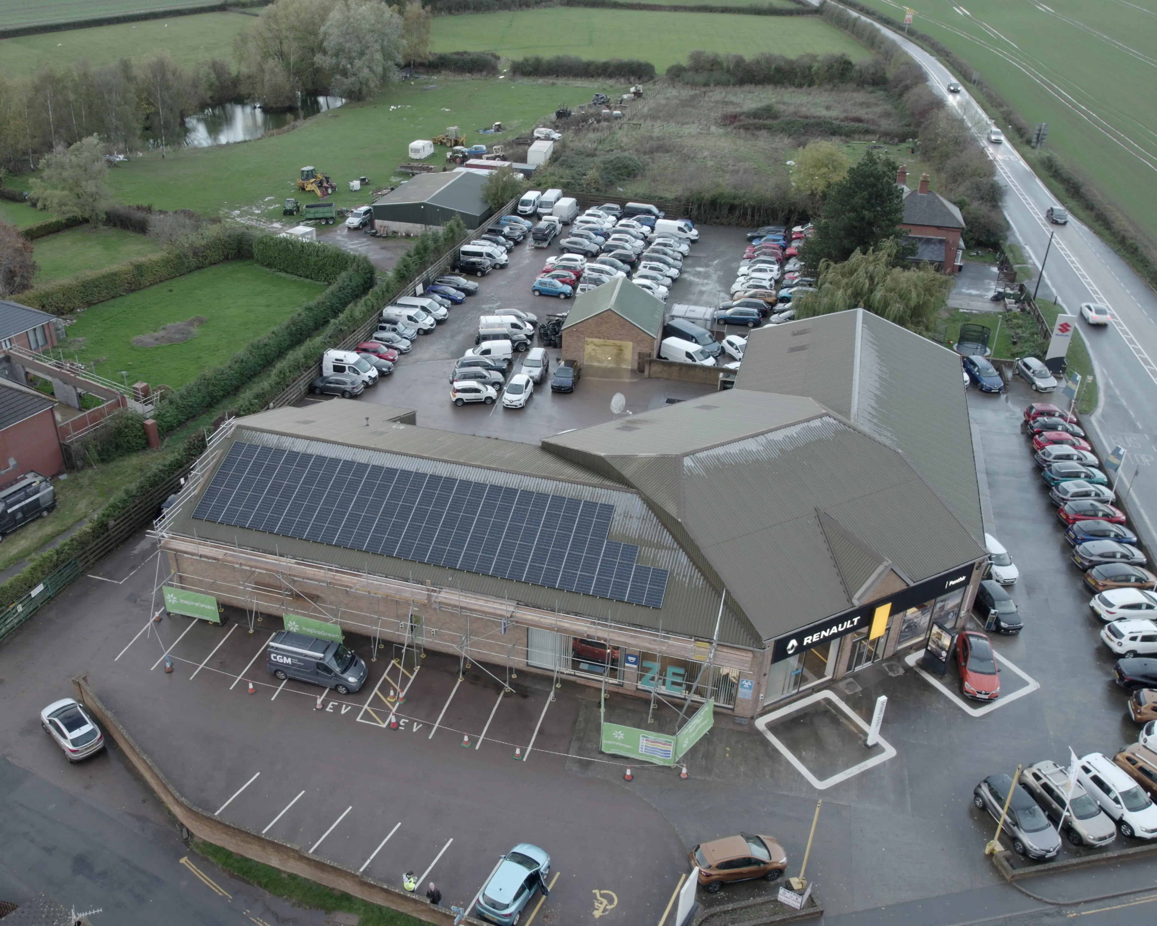 Commercial solar PV installation on a Renault car dealership rooftop, with panel arrays facing the forecourt and surrounding countryside.