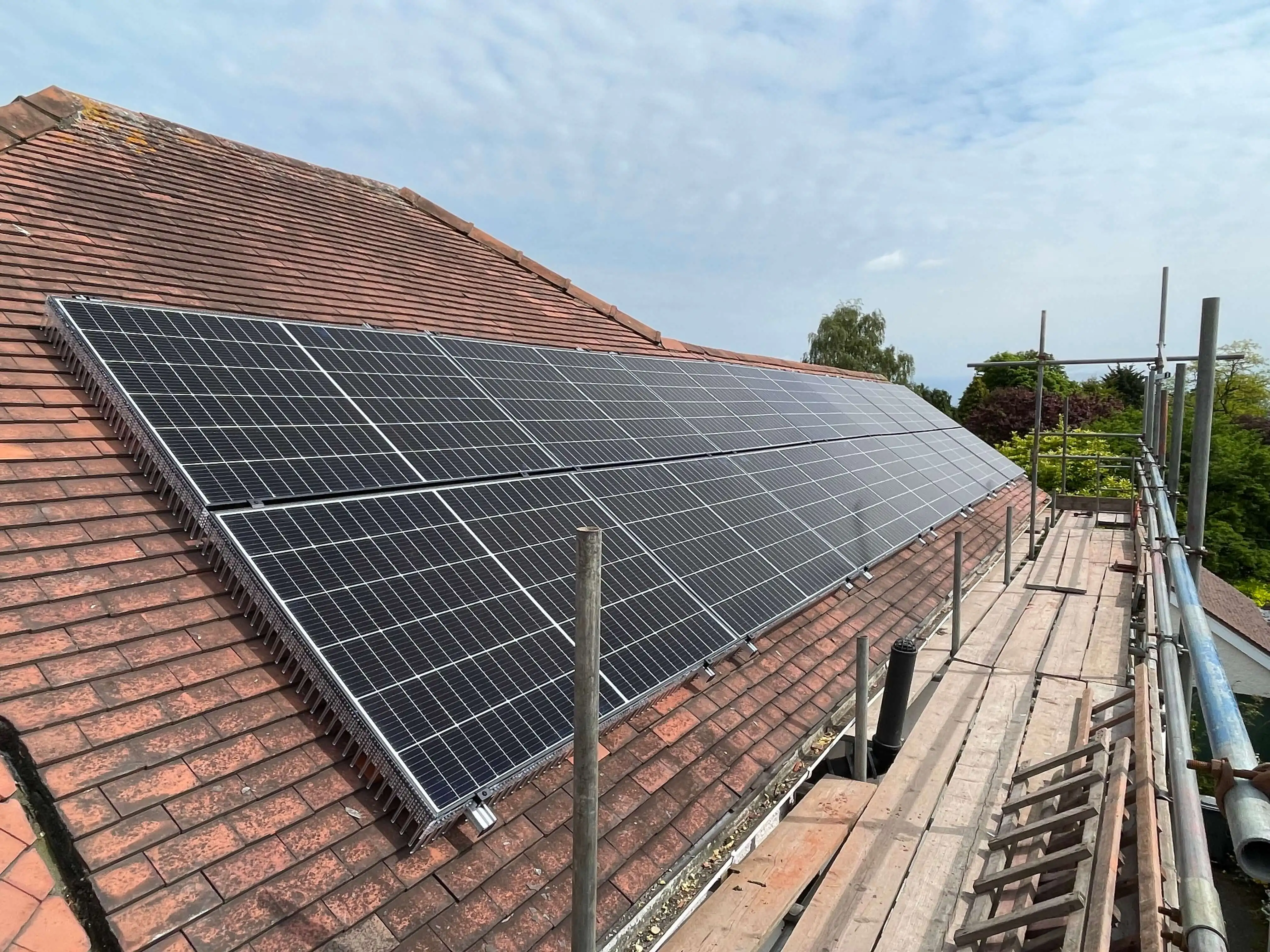 Solar panel installation on a domestic pitched roof, with roof-mounted PV panels across a tiled roof.