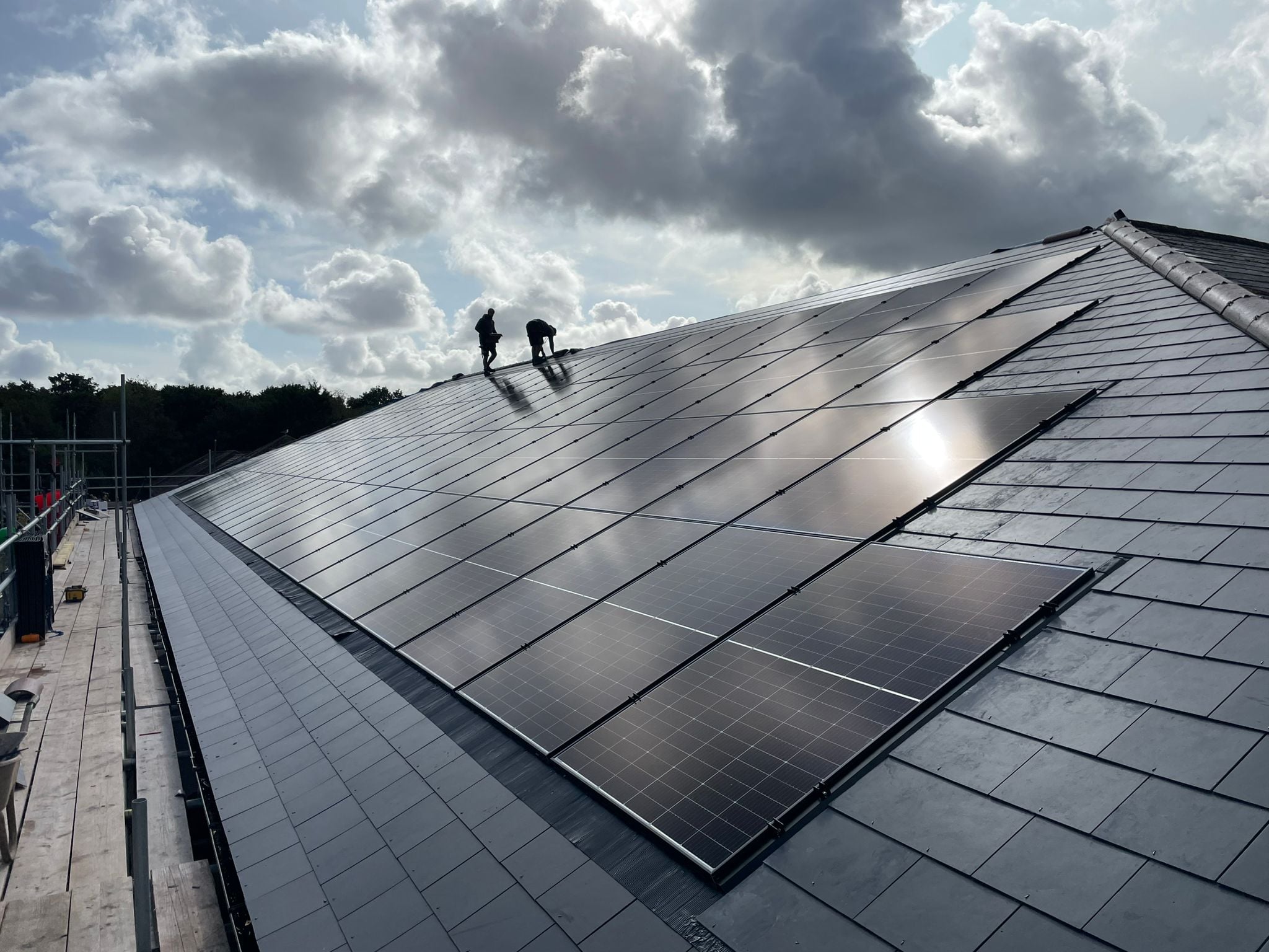 In-roof solar panel installation on a slate roof by professional installers, showing flush-mounted PV system integration.