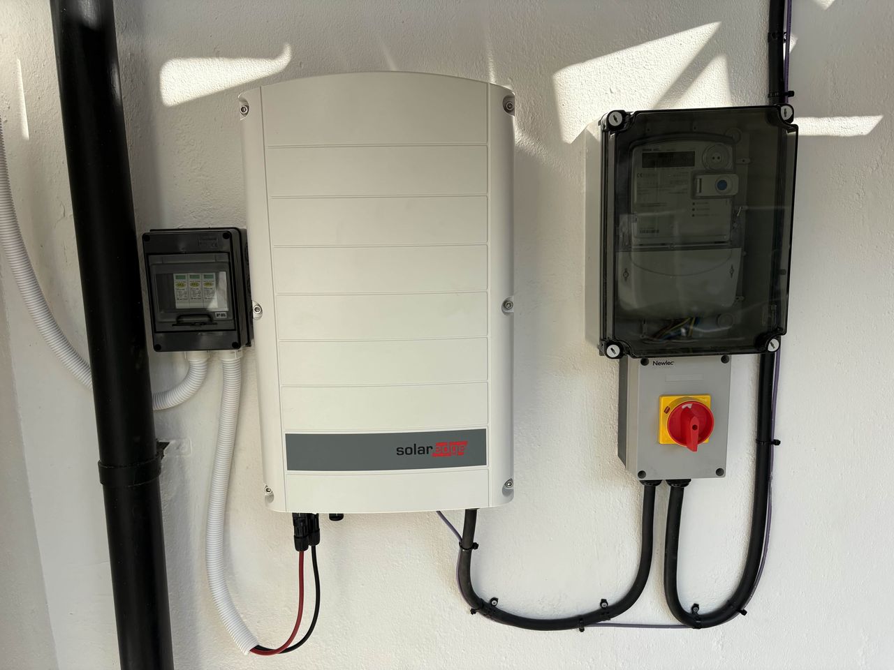 SolarEdge inverter, generation meter and AC isolator installed on an external wall, showing the key electrical components that require periodic inspection and planned replacement over a commercial solar system's lifetime.