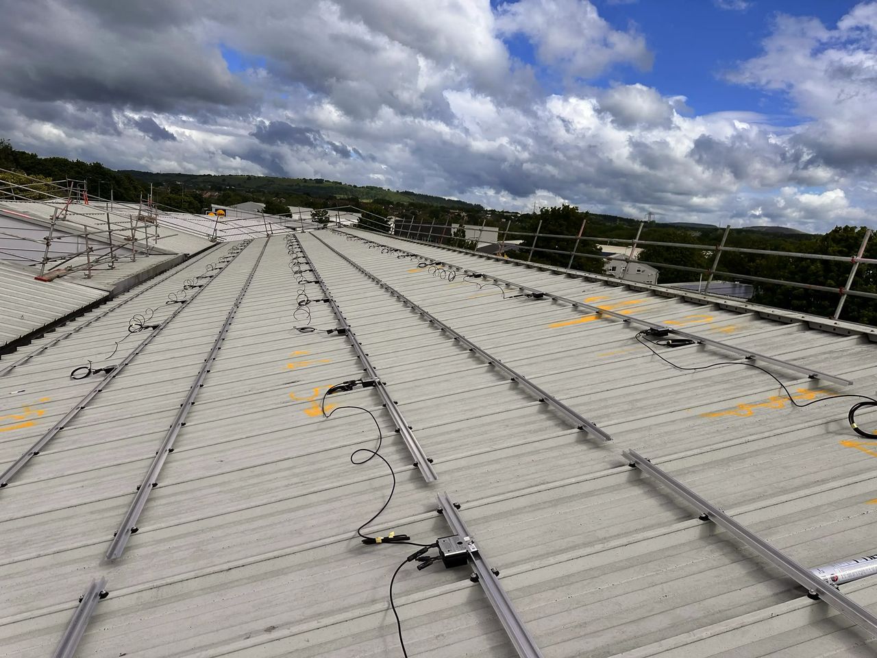 Solar panel rail mounting system and panel optimiser wiring installed on a commercial metal sheet roof at Vision Court, showing the structural components that underpin a solar array's 25-year lifespan.