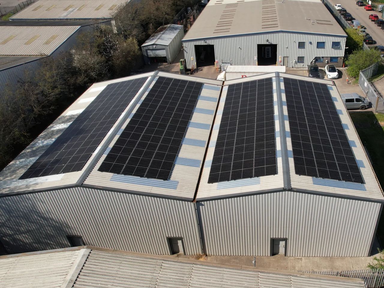 Commercial solar panels installed across the roof of an industrial unit, seen from above