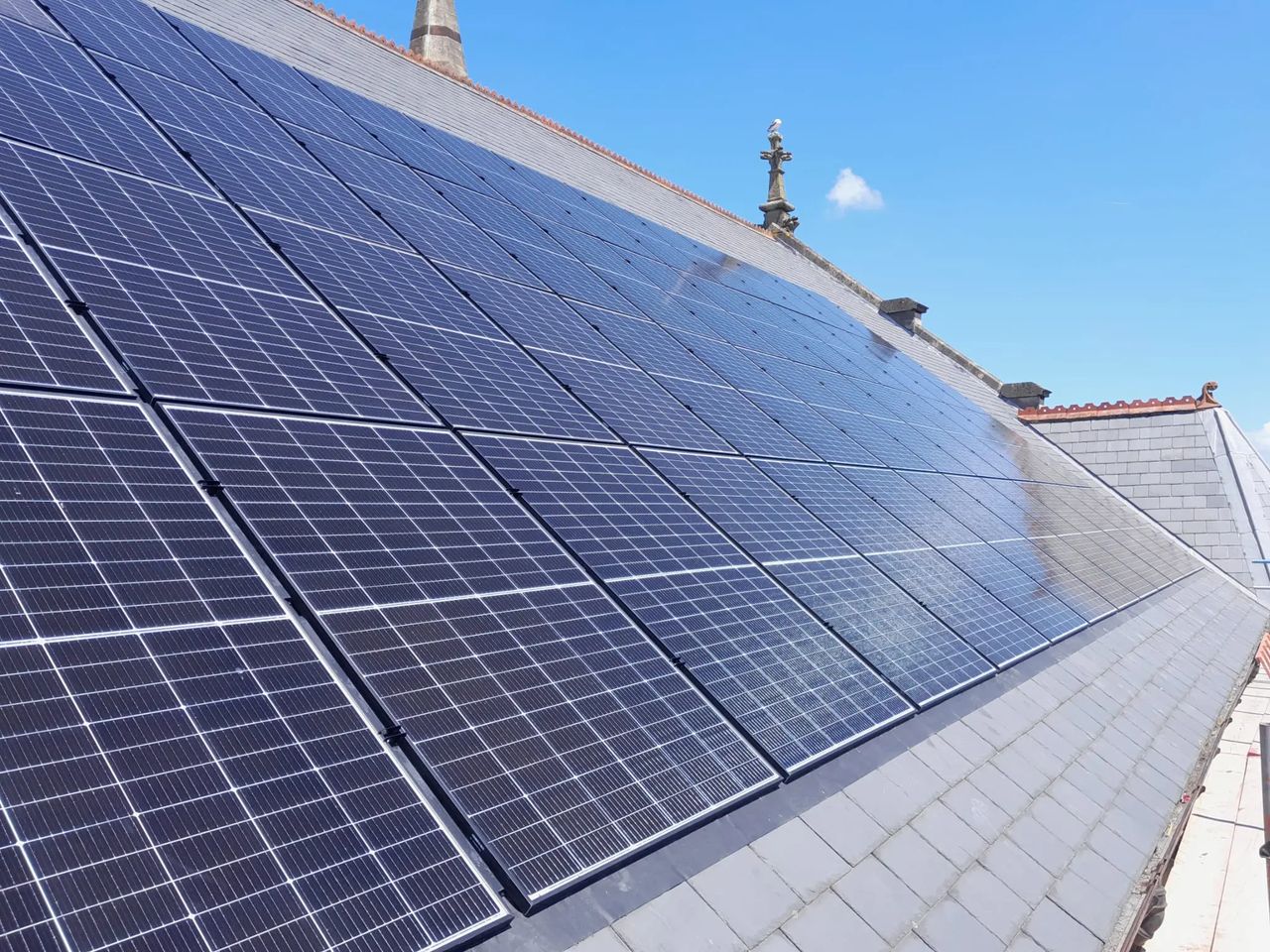 Integrated solar panel installation on a historic church roof, demonstrating renewable energy retrofit on a listed or heritage building.