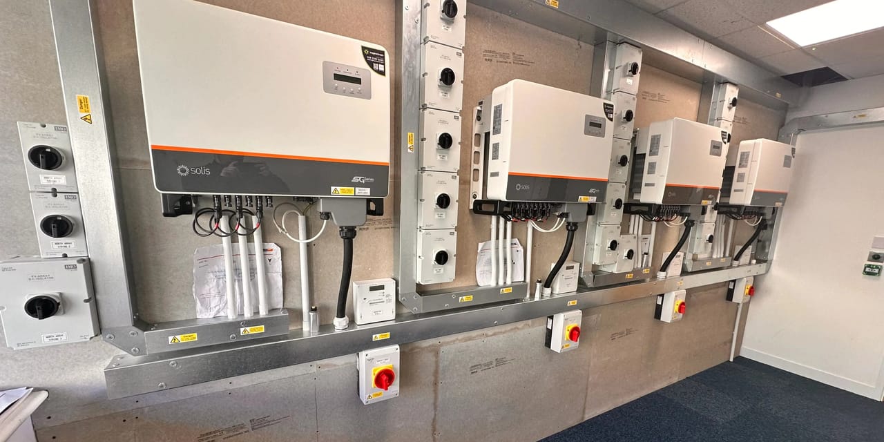 Wall-mounted plant room at New Directions with a row of Solis solar inverters, DC isolators, generation meter and labelled string isolators wired in by InspireGreen.