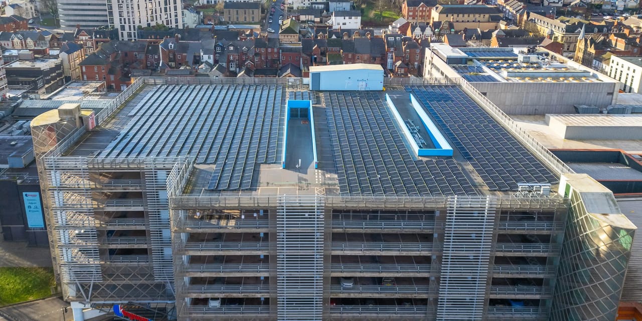 Aerial view of the rooftop solar PV array covering the top deck of the Kingsway multi-storey car park in Newport, with the town's terraced streets and buildings behind.