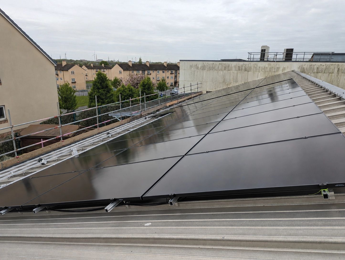 Solar panel installation on a community centre roof, with all-black PV panels on a pitched metal roof.