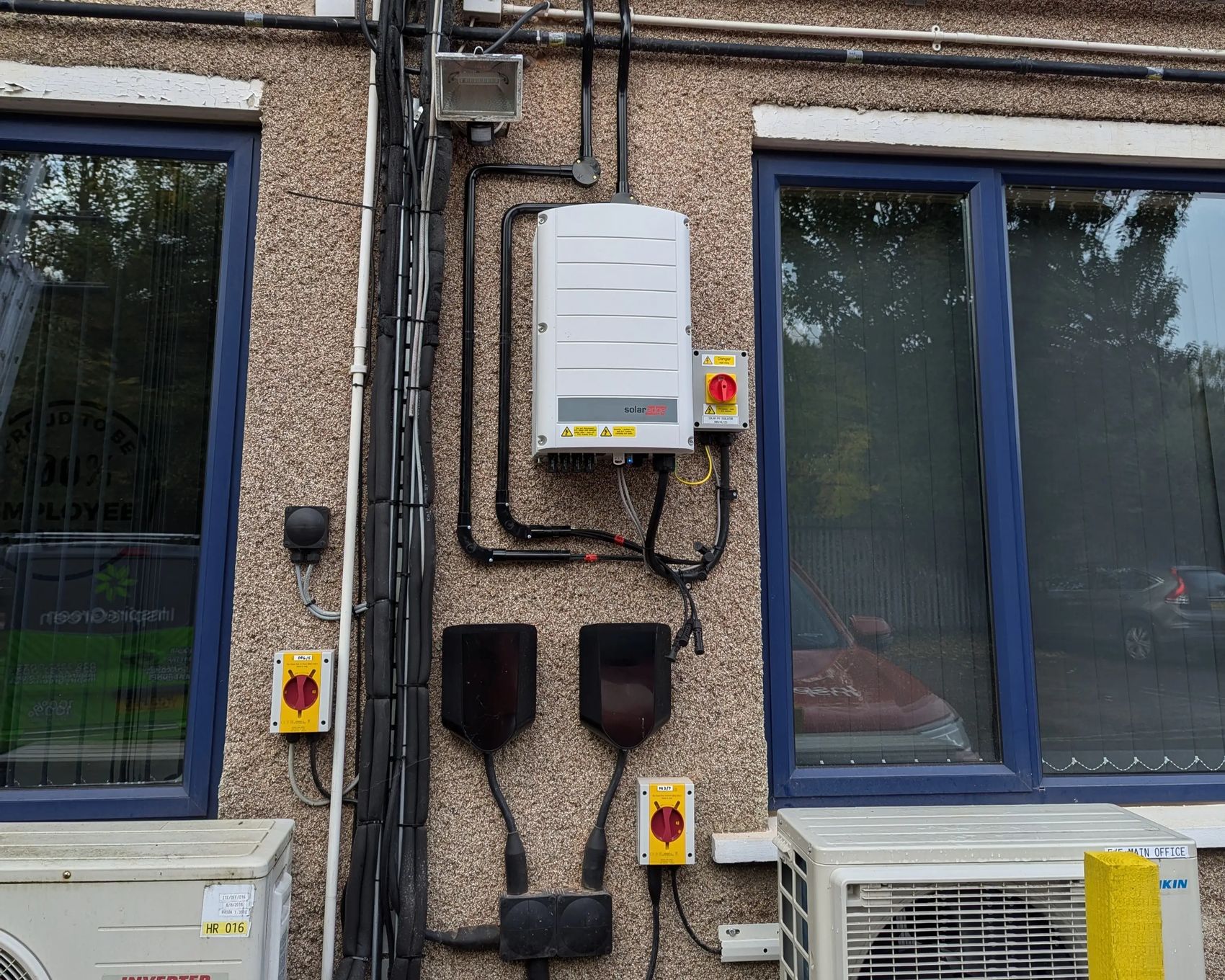 SolarEdge inverter and DC isolators mounted on the exterior wall of iTec Skills' head office in Cardiff, part of the completed solar PV system