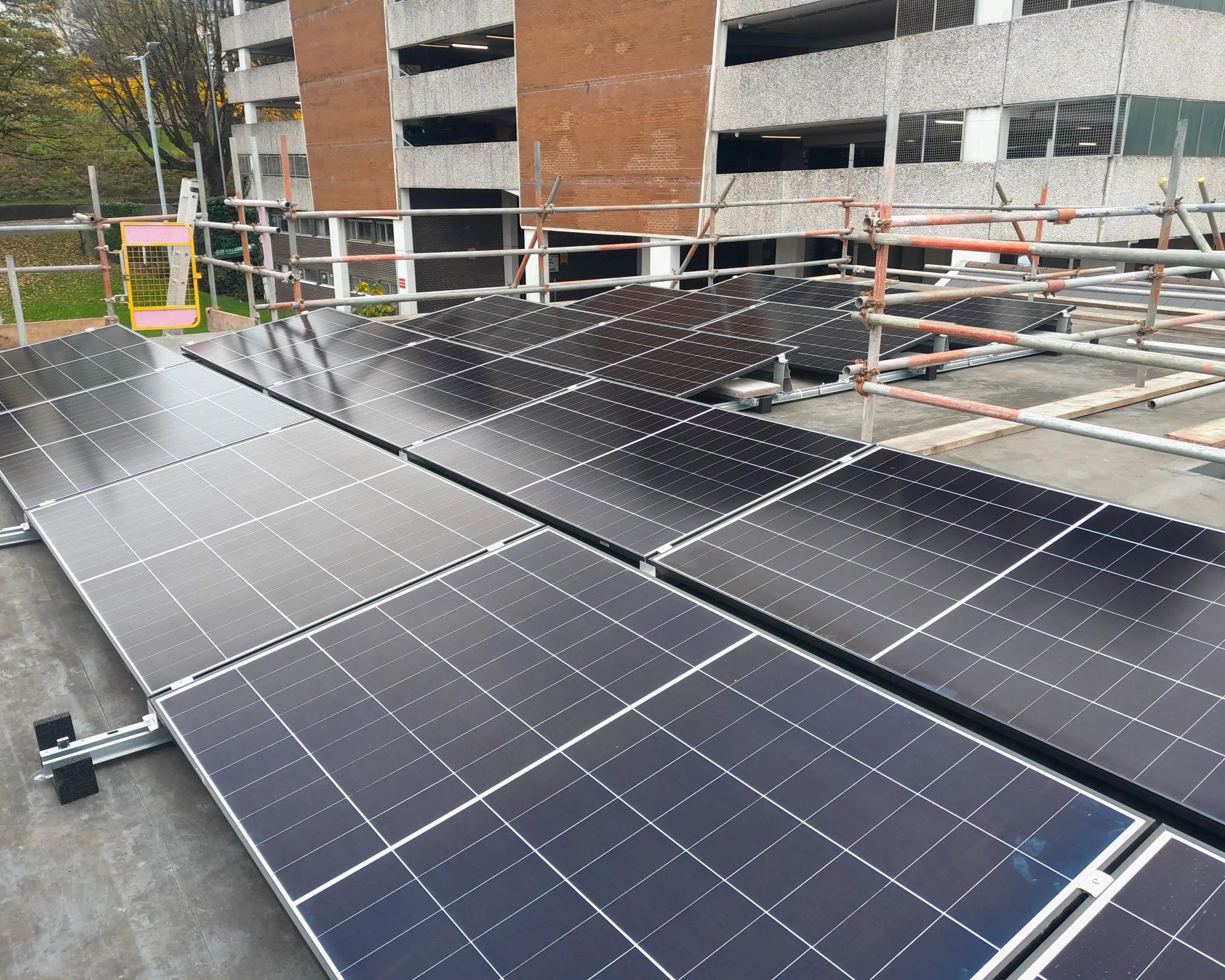 Solar PV panels installed on the flat roof of iTec Skills' training centre in Newport, with scaffolding and edge protection in place