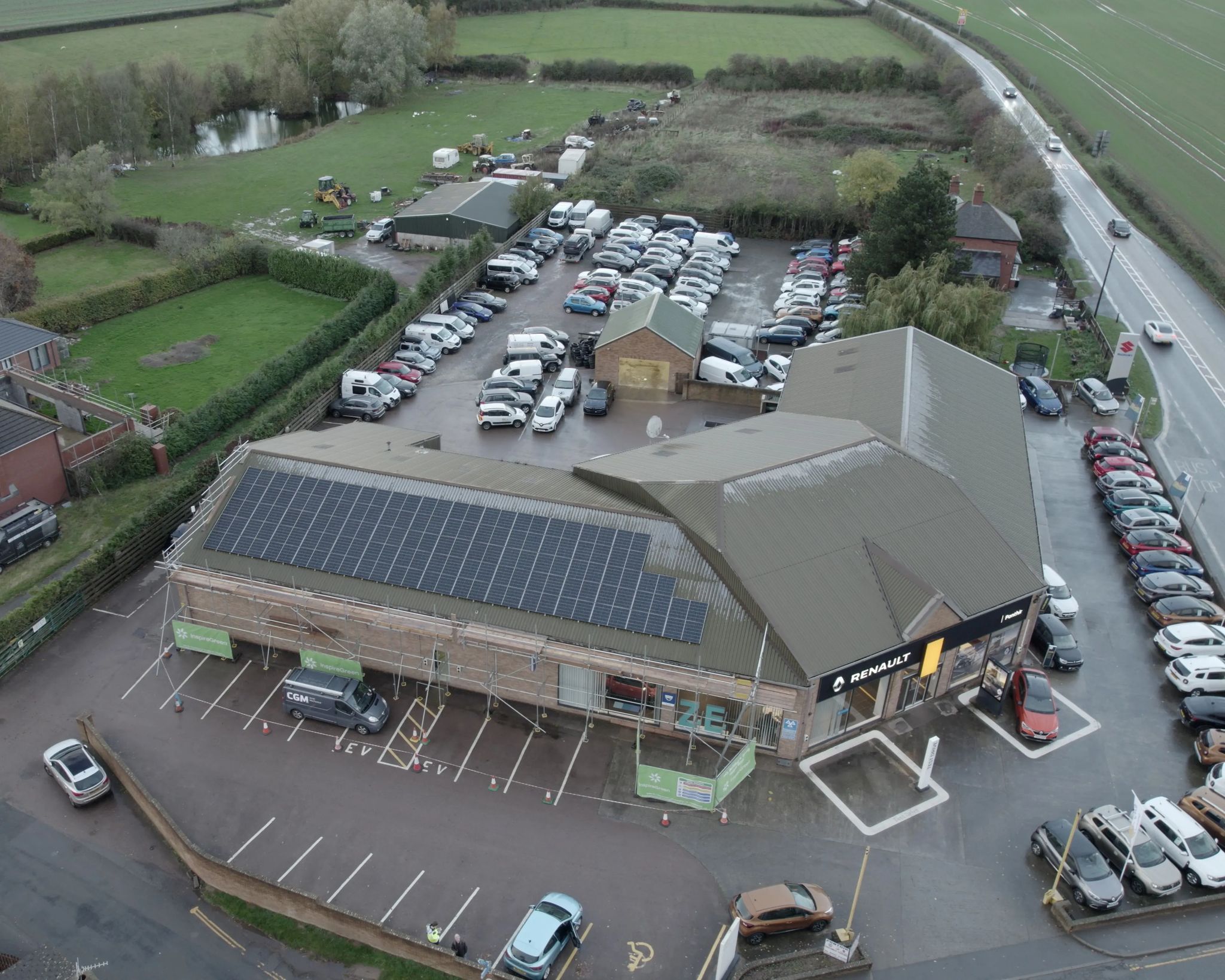 Commercial solar PV installation on a Renault car dealership rooftop, with panel arrays facing the forecourt and surrounding countryside.
