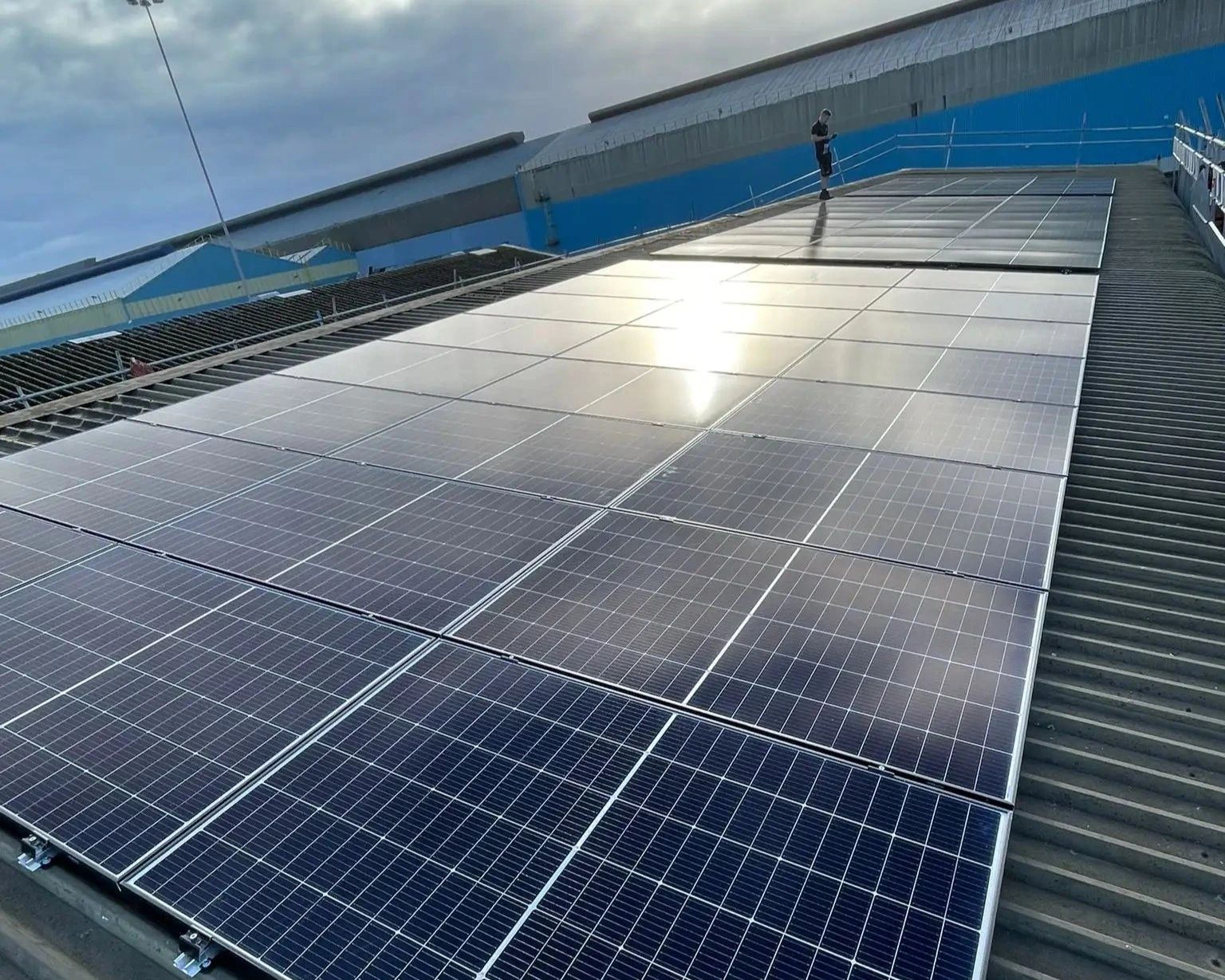 Commercial solar panel installation on a metal roof, with rows of roof-mounted PV panels catching the sun.