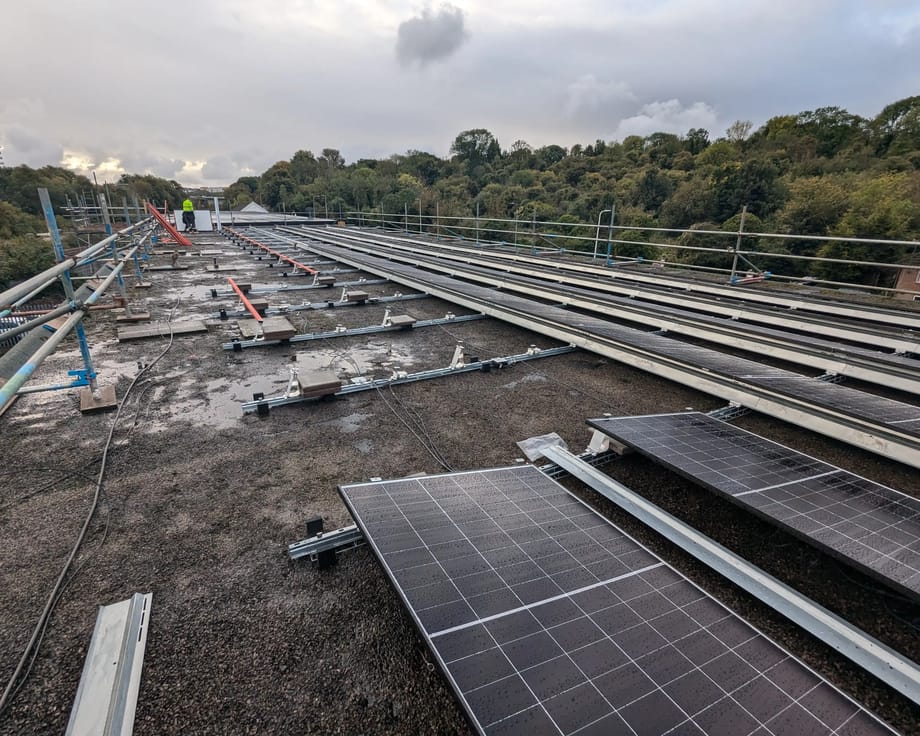 Mounting rails and the first solar panels being laid out on the flat roof of iTec Skills' head office in Cardiff during the installation