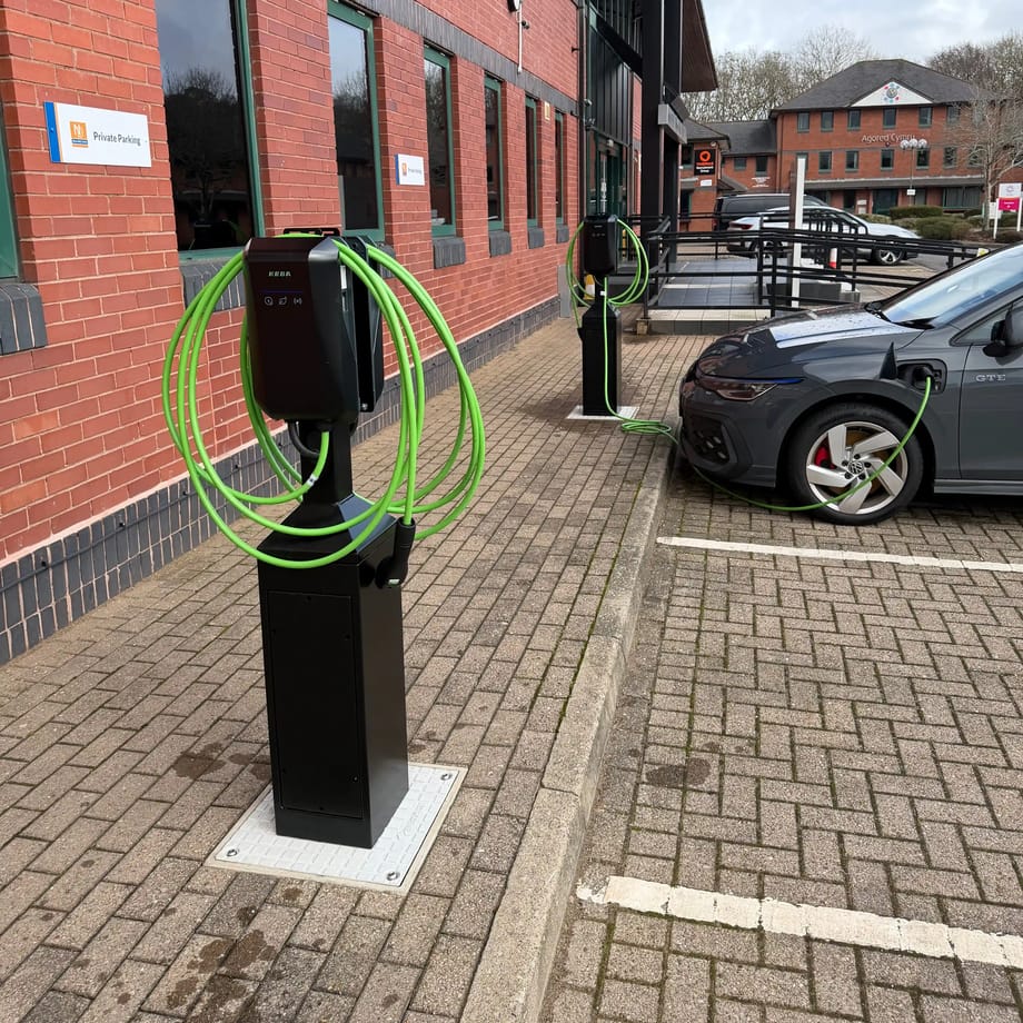Two EV charging towers in the car park at New Directions, Cardiff, one with a car connected and charging
