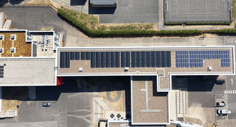 Overhead view of solar panels on the roof of Ysgol Gyfun Gwent Is Coed, with darker panels alongside a block of blue panels.